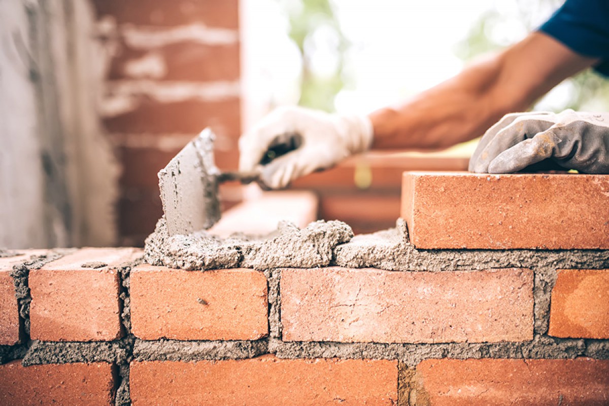 Photo d'un maçon construisant un mur en brique de terre cuite